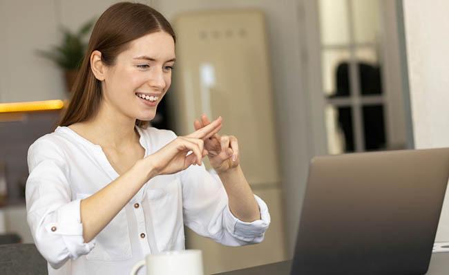 Una mujer se comunica en lengua de signos a través de una videollamada con su ordenador portátil