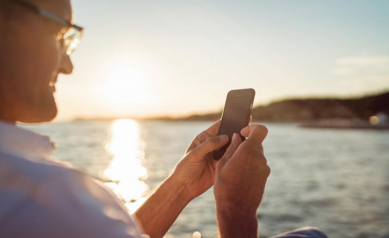 Un hombre mayor utiliza su smartphone junto al mar