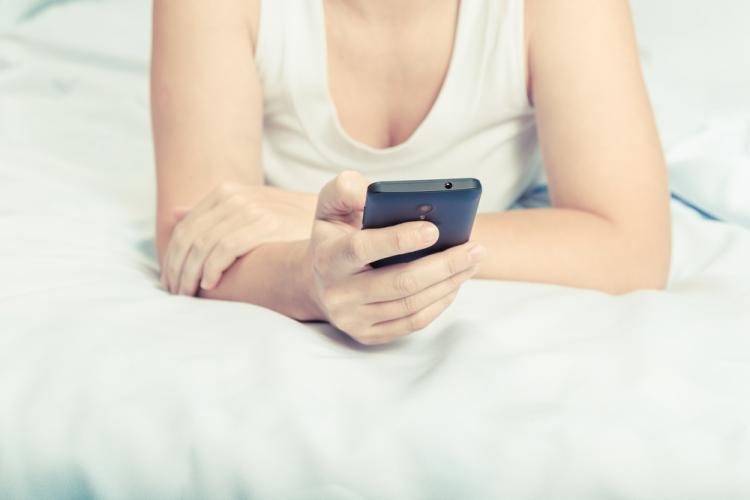 Una mujer utiliza su teléfono móvil en la cama