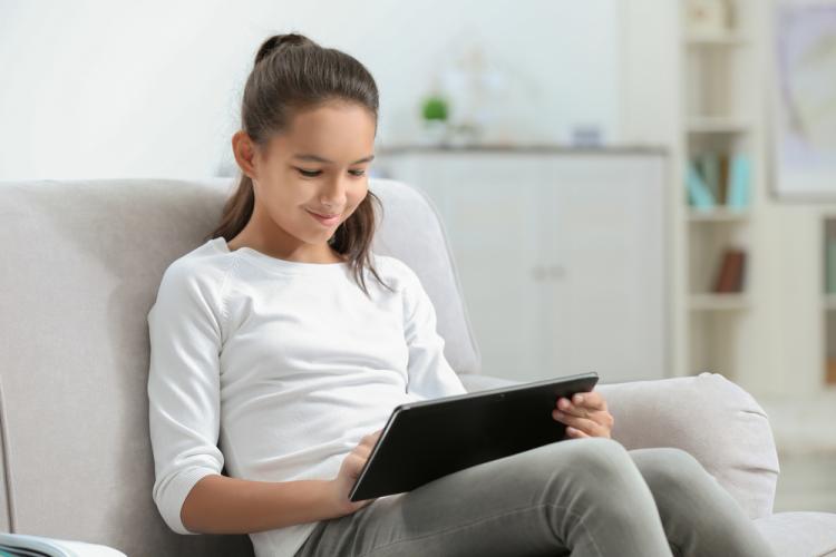 Una joven utiliza una tableta sentada en un sofá