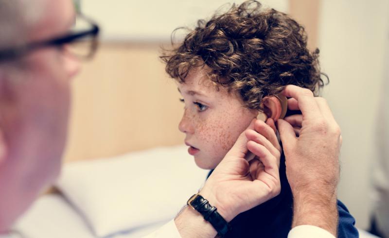 Un doctor coloca una prótesis a un niño con discapacidad auditiva