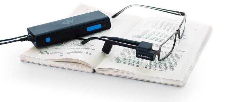 Unas gafas con el dispositivo OrCam incorporado sobre un libro abierto