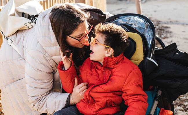 Una madre y su hijo con parálisis cerebral juegan de forma cariñosa