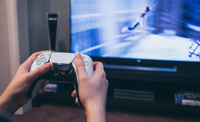 Fotografía de una persona jugando a una PlayStation 5 delante del televisor