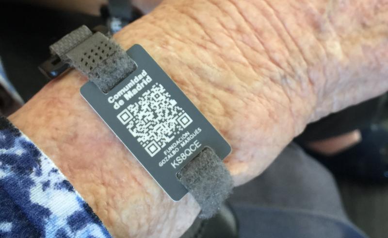 Detalle de una pulsera con código QR en la muñeca de una mujer mayor