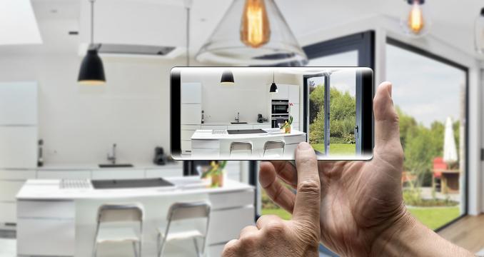 Unas manos sujetan un smartphone dentro de una casa moderna