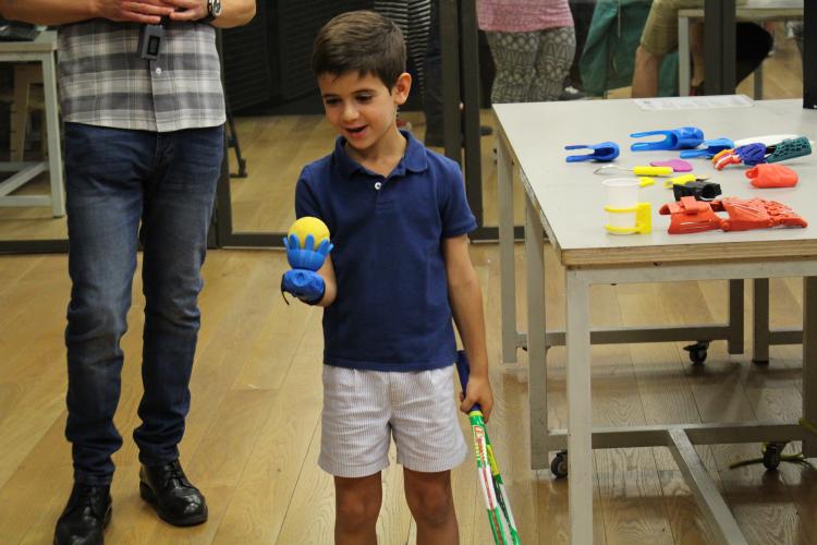 Un niño utiliza la prótesis SuperGiz para sujetar una pelota de tenis