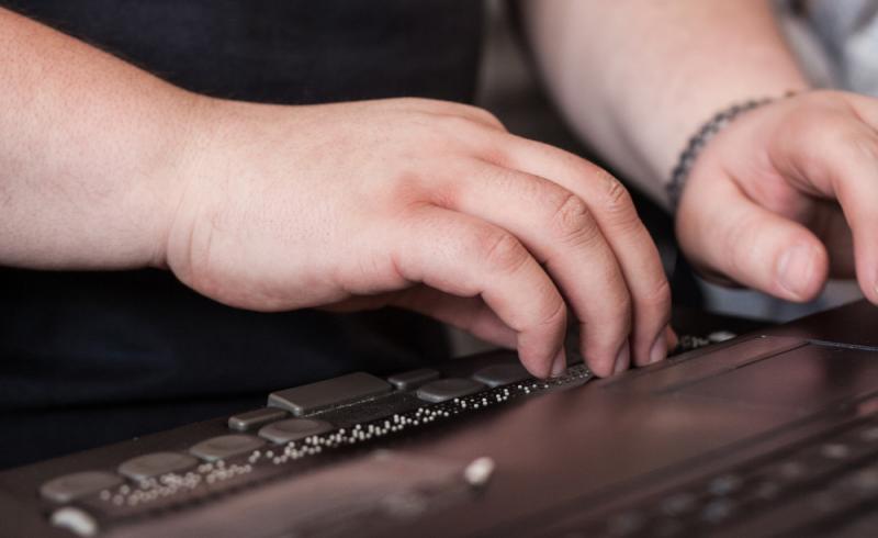 Una persona ciega utiliza la línea braille conectada a un ordenador portátil