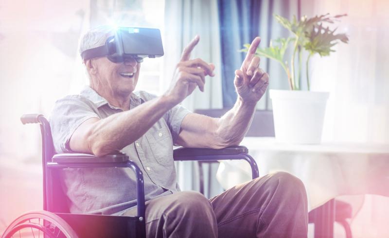 Una persona mayor en silla de ruedas utiliza unas gafas de realidad virtual