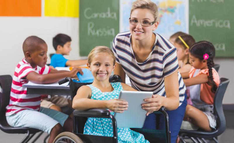 Una profesora y una alumna en silla de ruedas utilizan una tableta