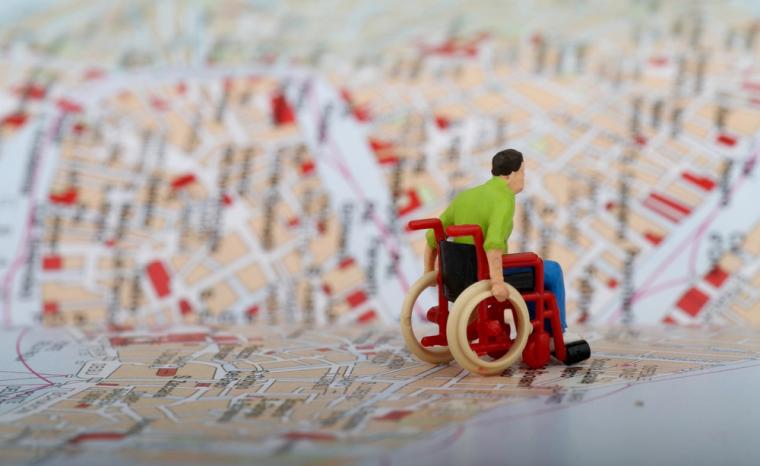 Una figura de una persona con discapacidad en silla de ruedas sobre el mapa de una ciudad