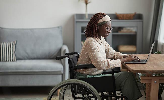 Una mujer en silla de ruedas utiliza un ordenador port&aacute;til