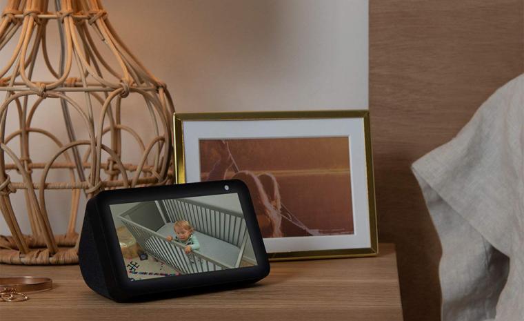 Imagen comercial de un Amazon Echo Show 5 sobre una mesilla al lado de una cama