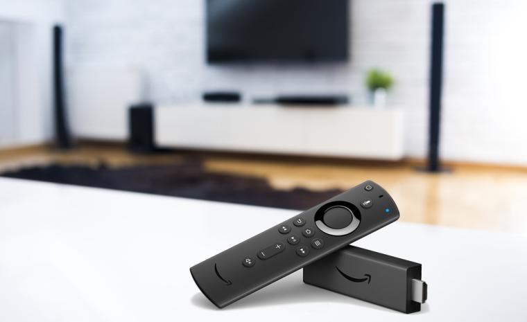 Uno de los nuevos Fire TV Stick y el mando colocados encima de una mesa en un sal&oacute;n