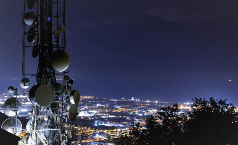 Fotograf&iacute;a de una antena de telefon&iacute;a m&oacute;vil a las afueras de una ciudad de noche