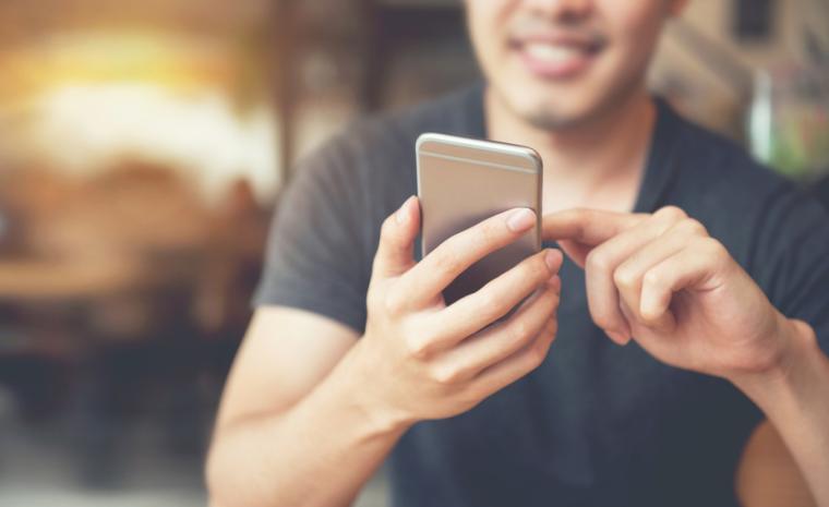 Un joven utiliza una aplicaci&oacute;n en un tel&eacute;fono m&oacute;vil