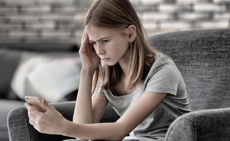 Una ni&ntilde;a que ha sufrido acoso utiliza un tel&eacute;fono m&oacute;vil