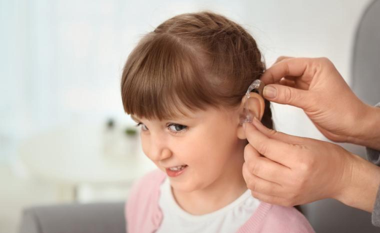 Una persona coloca un aud&iacute;fono a una ni&ntilde;a