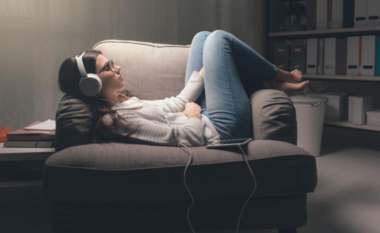 Una joven escucha un audiolibro en un sill&oacute;n