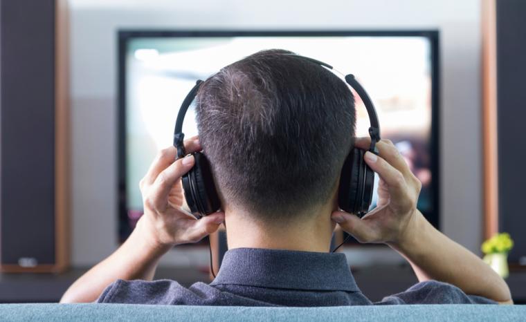 Una persona con auriculares sentada frente a un televisor
