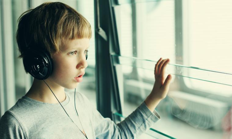 Un ni&ntilde;o mira por una ventana con unos auriculares puestos