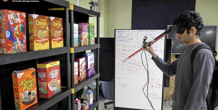 Una persona con antifaz prueba el prototipo de bast&oacute;n inteligente en una tienda