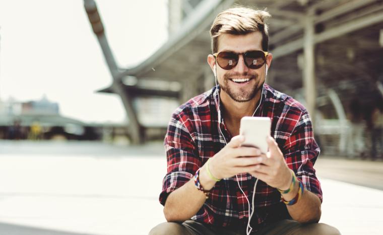 Un joven escucha su smartphone con unos auriculares
