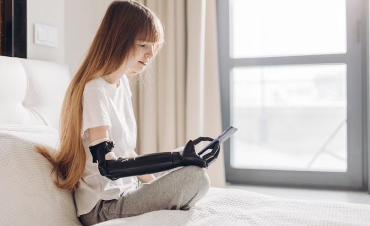 Una joven con una pr&oacute;tesis en el brazo utiliza un tel&eacute;fono m&oacute;vil