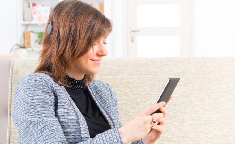 Una mujer joven con implante coclear utiliza su smartphone