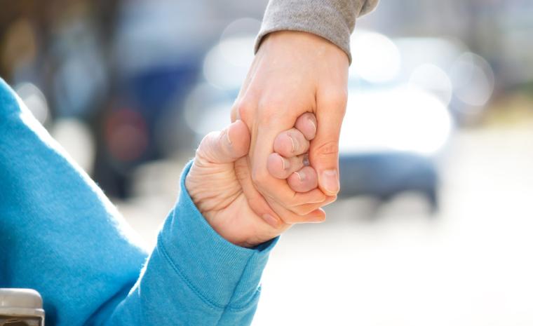 Una persona andando y otra en silla de ruedas se dan la mano