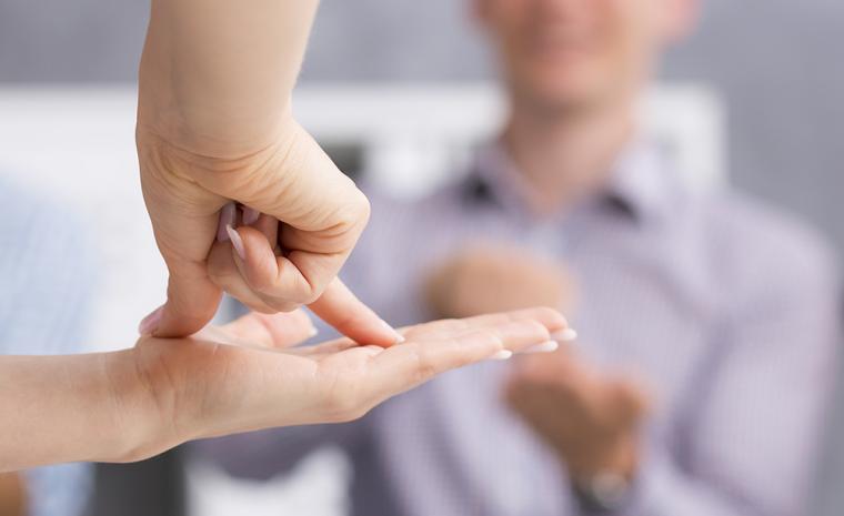 Primer plano de las manos de una persona signando delante de otras personas