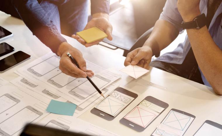 Varias personas trabajan en el dise&ntilde;o de una app para tel&eacute;fono m&oacute;vil