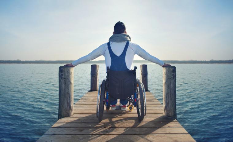 Una persona en silla de ruedas en un muelle de un lago