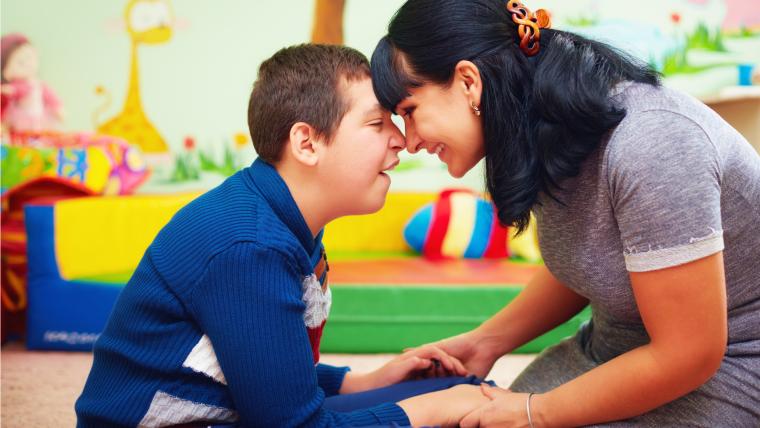 Una madre en actitud cari&ntilde;osa con su hijo con discapacidad