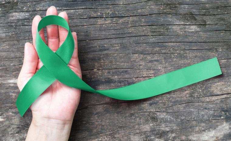 Una mano sostiene un lazo verde se&ntilde;al del D&iacute;a Mundial del Glaucoma