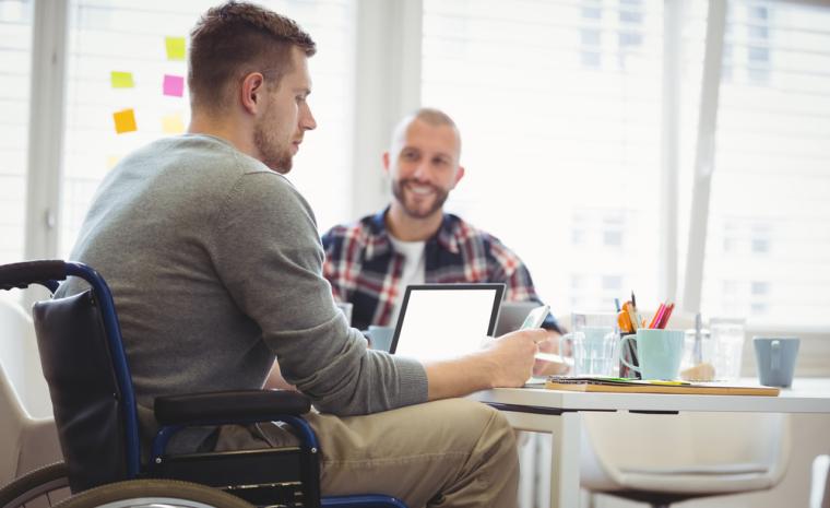 Un joven en silla de ruedas utiliza distinta tecnolog&iacute;a en su puesto de trabajo