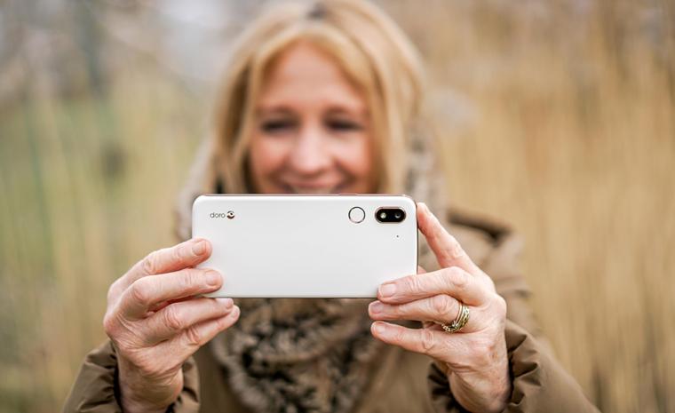 Una mujer mayor toma una foto con un Doro 8080