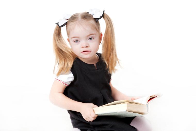 Ni&ntilde;a con s&iacute;ndrome de Down leyendo un libro