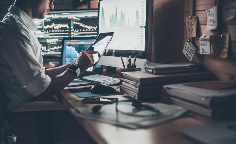 Un hombre en su puesto de trabajo rodeado de dispositivos tecnol&oacute;gicos
