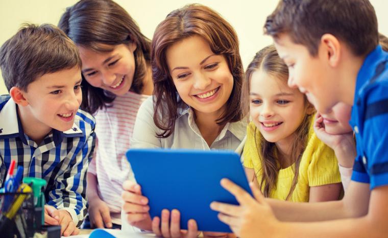 Varios alumnos y una profesora utilizan una tableta en el aula