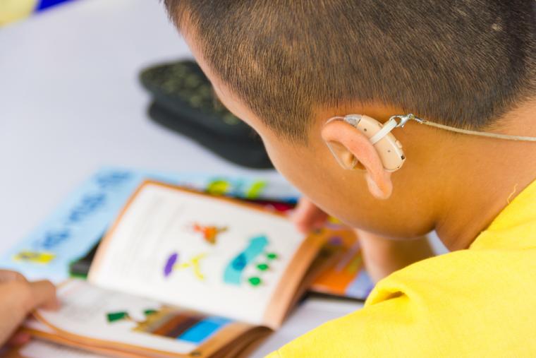 Un ni&ntilde;o que utiliza un aud&iacute;fono mirando un libro