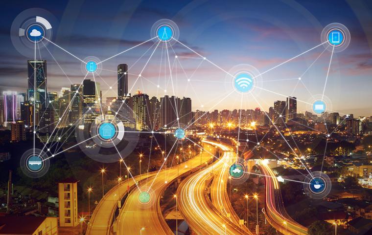 Vista nocturna de una ciudad con iconos tecnol&oacute;gicos superpuestos dando la idea de interconectividad