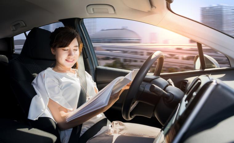 Interior de un coche aut&oacute;nomo en el que la conductora lee un libro