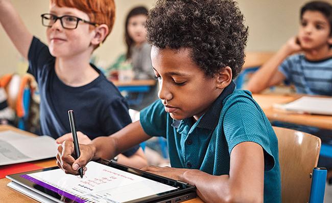 Un ni&ntilde;o utiliza una tableta de Microsoft y las herramientas de aprendizaje en la escuela