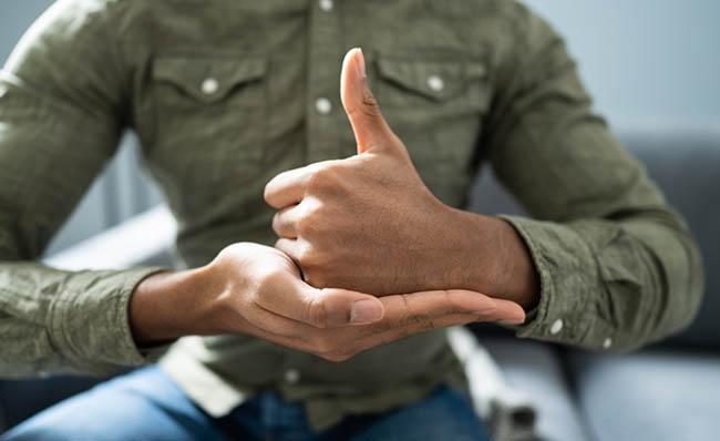 Un hombre se comunica mediante lengua de signos sentado en un sof&aacute;