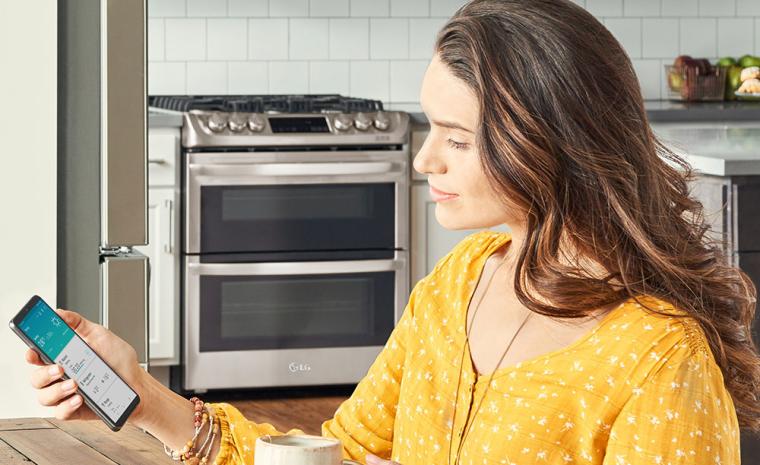 Fotograf&iacute;a comercial de una mujer utilizando la app ThinQ en una cocina