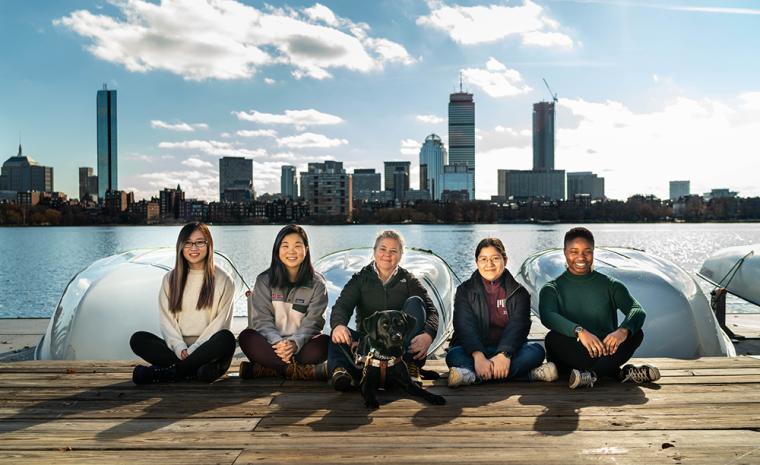 El equipo de estudiantes del MIT junto a Pauline Dowell (centro) en un muelle con varias embarcaciones detr&aacute;s