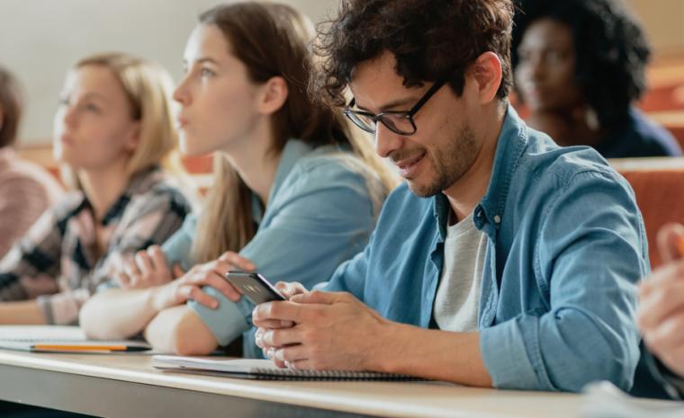 Un joven utiliza su smartphone en una clase en la universidad