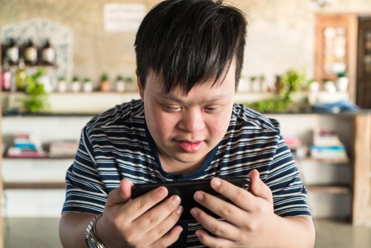 Un joven con sindrome de Down utiliza un tel&eacute;fono m&oacute;vil
