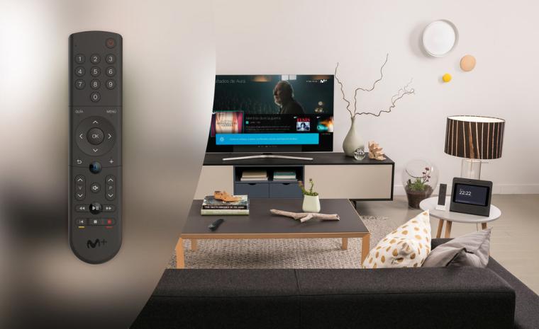 Imagen comercial del mando con control de voz de Movistar junto a la fotograf&iacute;a de un sal&oacute;n con un televisor